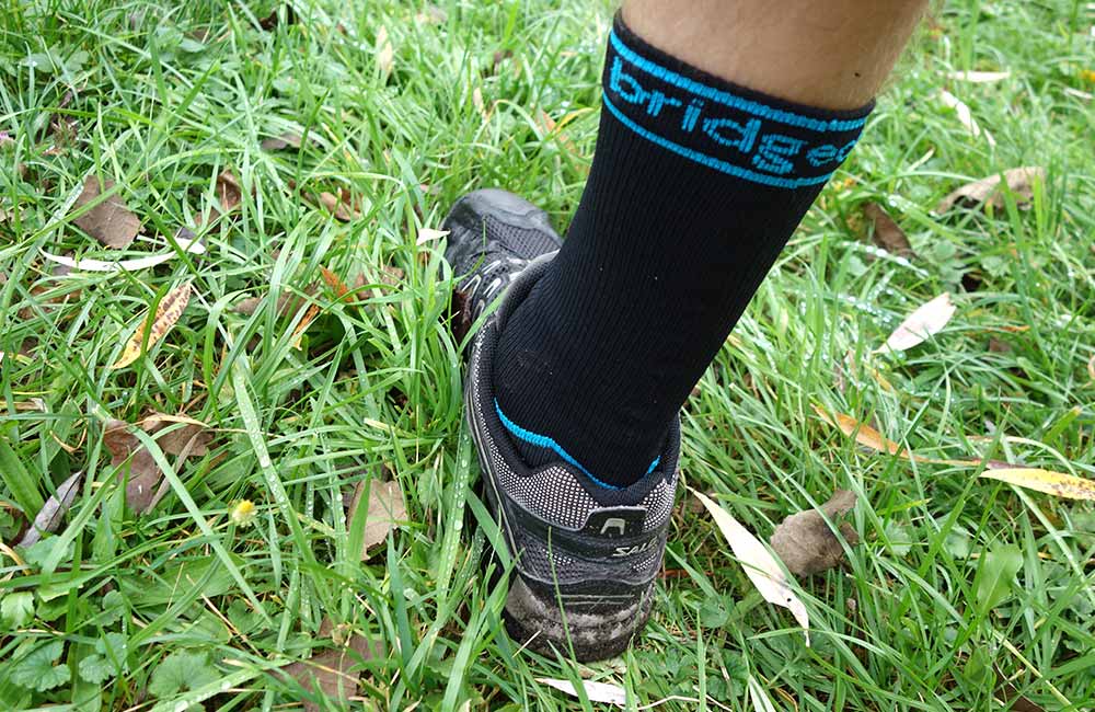 Skarpety wodoszczelne Bridgedale StormSock w mokrej trawie.