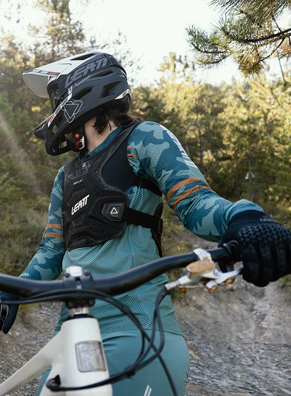Rowerzysta enduro w kasku, ocharniaczu torsu oraz rękawiczkach na rowerze.