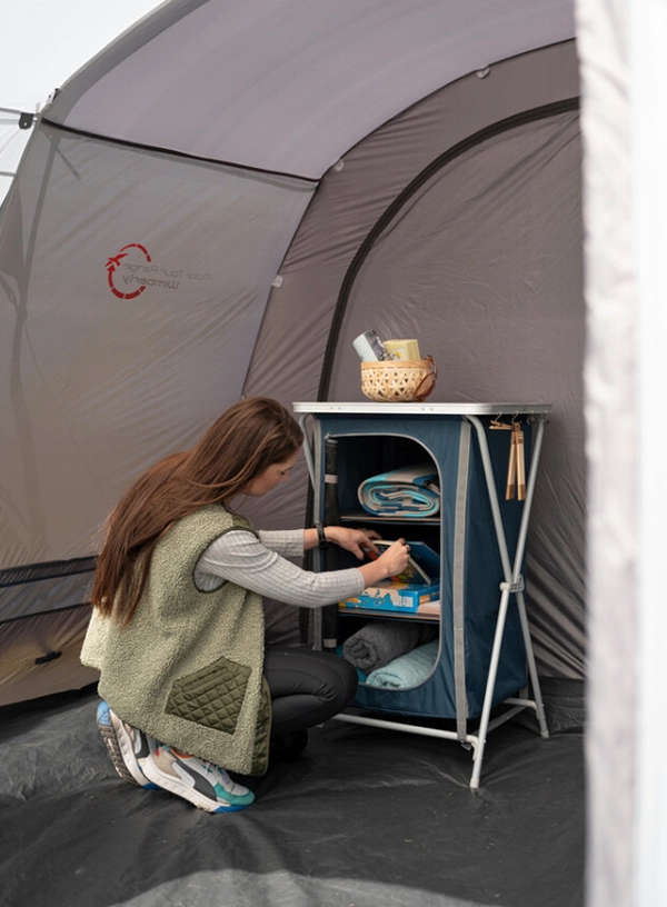 Kobieta układająca rzeczy w szafce na campingu.