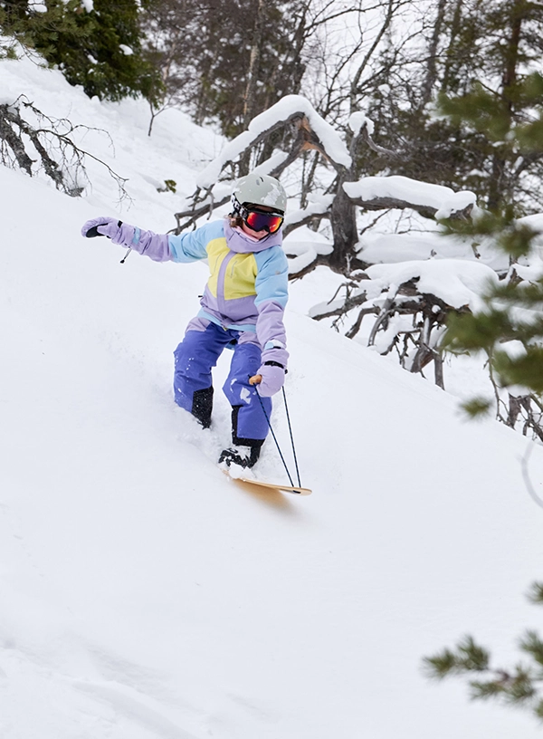 Dziecko zjeżające na snowboardzie.